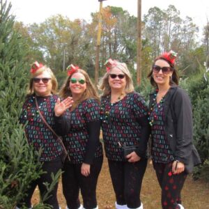 4 woman dressed as elves in front of christmas trees